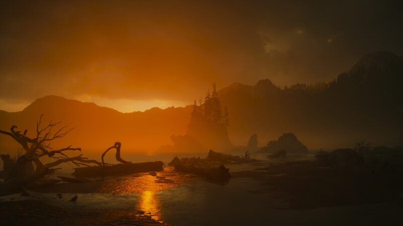 A foggy landscape at dusk features a glowing orange sky, silhouetted mountains, a reflective water surface, and a weathered log along the shore.