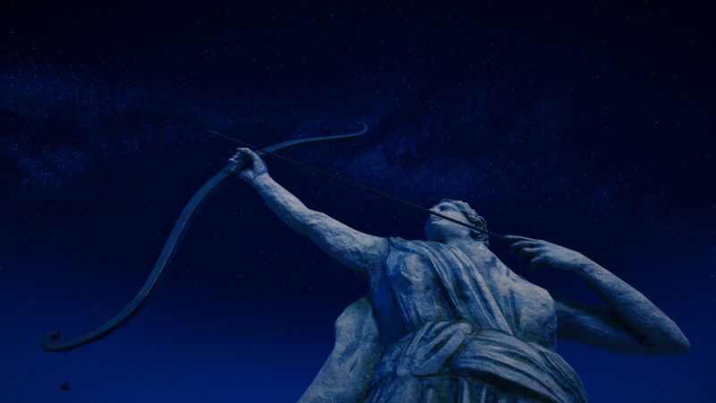 A towering statue of a woman with a bow drawn, set against a starry night sky, emphasizing its grandeur and the tranquil atmosphere of the surrounding environment.
