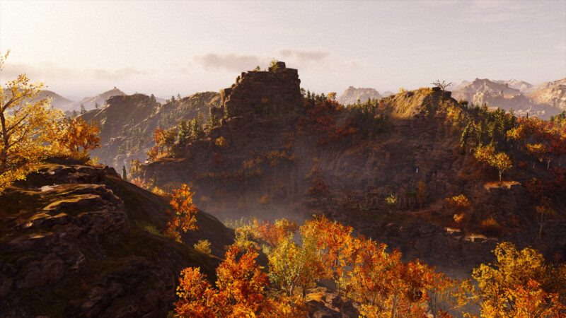 A stunning autumn landscape features rugged hills adorned with vibrant orange and yellow foliage, bathed in soft sunlight, with distant mountainous terrain and misty valleys in the background.