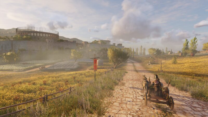 A chariot pulled by horses travels along a cobblestone road, surrounded by vibrant fields and distant ruins under a partly cloudy sky.