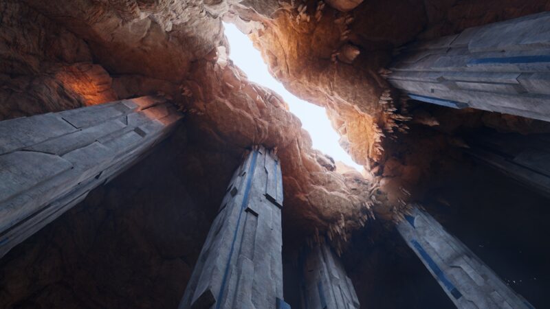 A cavernous space featuring majestic stone pillars rising towards a partially open ceiling, allowing soft light to filter through the rugged rock formations above.
