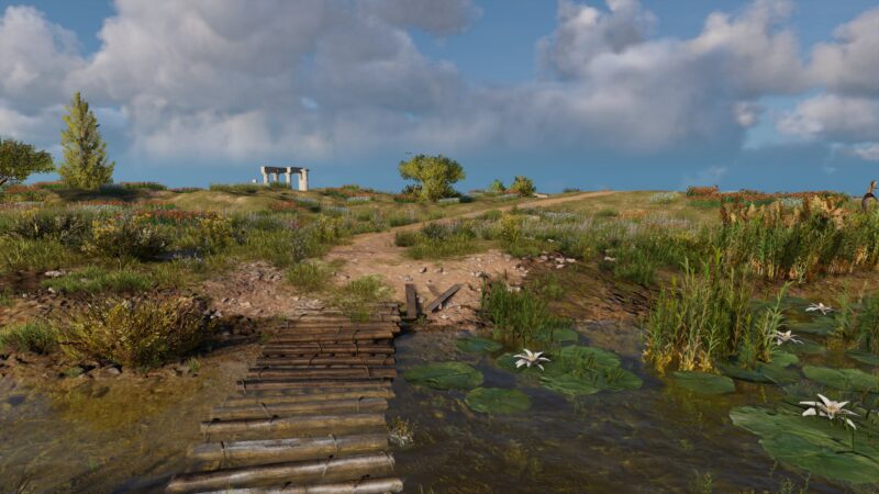 A dirt path leads through a verdant landscape with wildflowers, lily pads on water, a wooden bridge, and distant ruins under a partly cloudy sky.