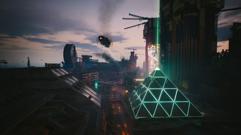 A futuristic cityscape features a large illuminated pyramid, flying vehicle emitting smoke, and a vibrant skyline with construction cranes and towering buildings against a dusk sky.