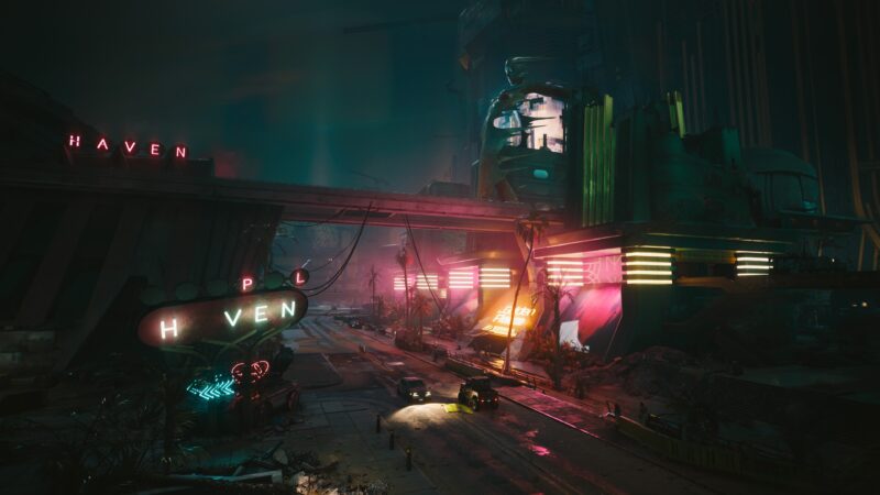 A neon-lit urban landscape features towering structures with glowing signage, a dimly lit road, and stylized, futuristic vehicles amidst a gritty, industrial backdrop.