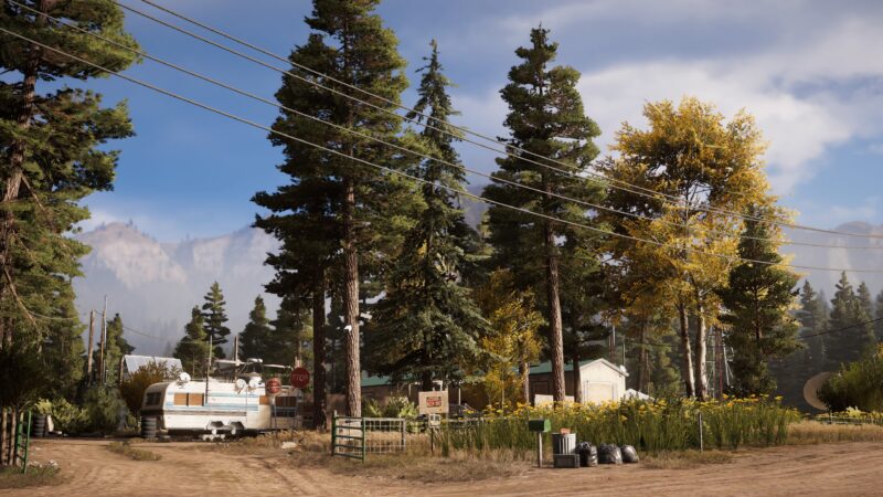 A tranquil rural scene features a white trailer amidst tall green pines and autumn trees, with power lines overhead and a dirt path leading through yellow flowers.