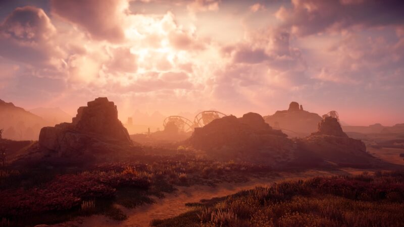 A serene landscape features rocky formations under a sunset, with dramatic clouds illuminating the scene, while remnants of a roller coaster emerge from the foreground foliage.