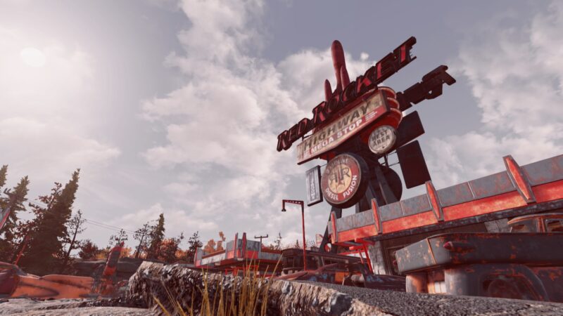 A weathered gas station sign towers above a rocky landscape, featuring a bright red "Red Rocket" logo, surrounded by sparse trees and a cloudy sky.