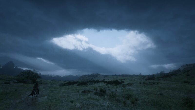 A lone rider traverses a grassy landscape under a dramatic sky filled with dark clouds and a distinct, bright opening, casting beams of light onto the terrain.