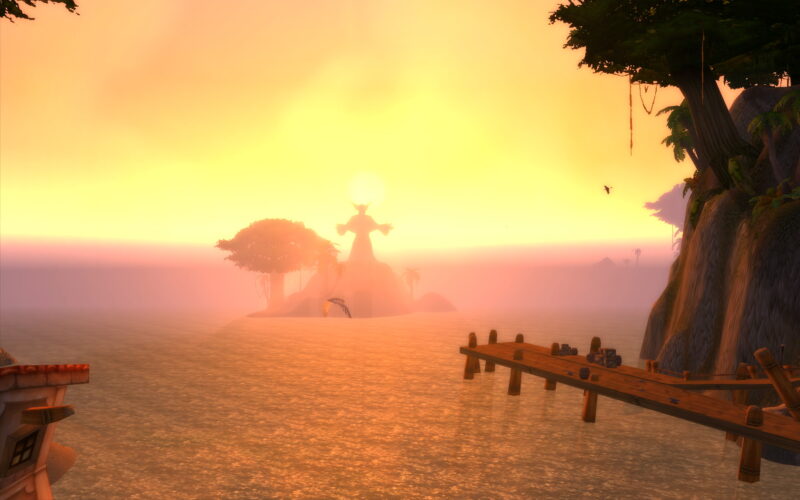 A serene sunset illuminates the horizon over a tranquil sea, with silhouetted trees and a distant island featuring a large statue, casting a peaceful atmosphere.