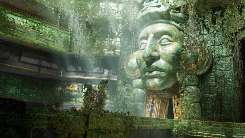 A large ancient stone face covered in moss and vines dominates a lush, overgrown temple interior, with intricate green carvings illuminated by ethereal light.
