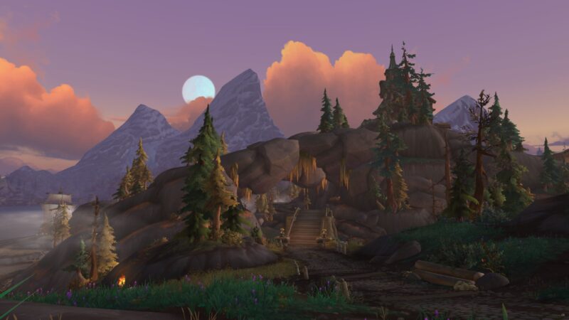 A serene landscape featuring mountains under a sunset sky, with a rocky archway leading to a pathway, surrounded by lush greenery and scattered trees.