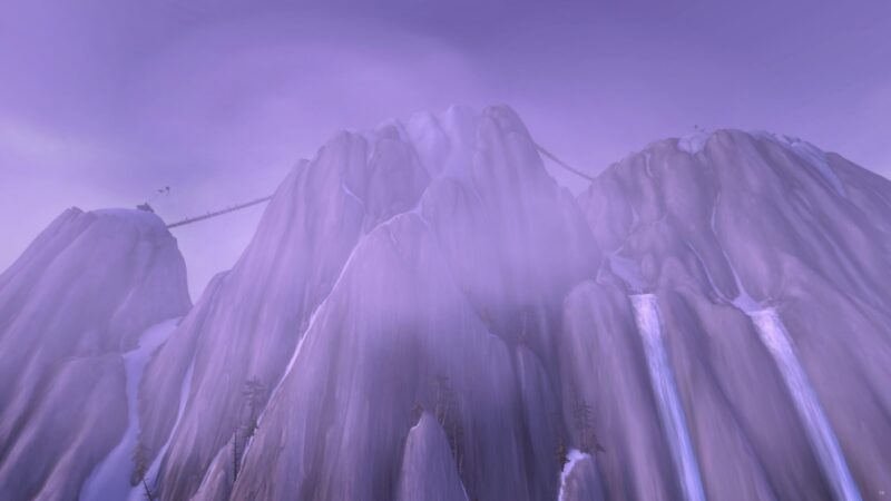 A misty mountain landscape features towering, rocky peaks partially shrouded in fog, with cascading waterfalls visible and a faint bridge spanning across the heights.