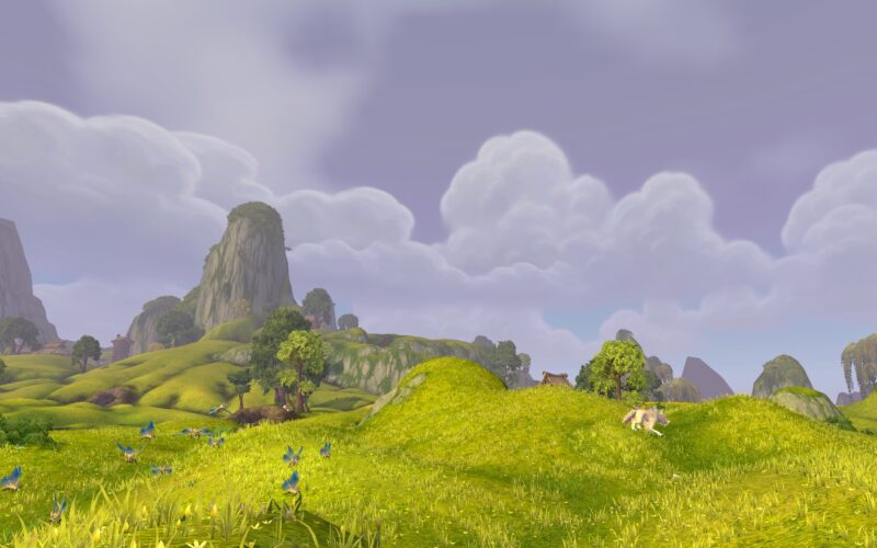 A lush, rolling landscape features green hills, scattered trees, and vibrant blue flowers under a cloudy sky, creating a serene and picturesque environment.