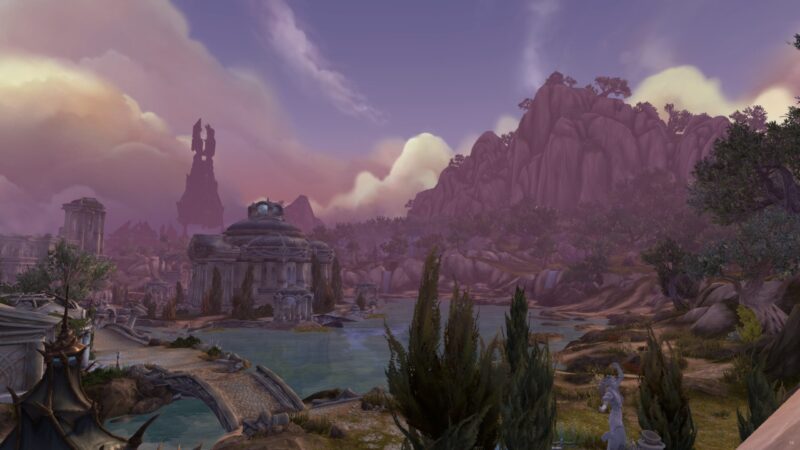 A serene landscape features a calm lake surrounded by rocky hills, ancient ruins, and lush vegetation under a pastel sky with soft pink and purple hues.