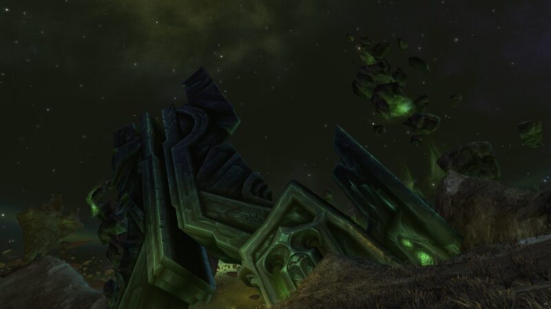 A massive, dark green structure lies crumbled on a rocky terrain, illuminated by eerie green lights against a starry, dark sky filled with floating debris.